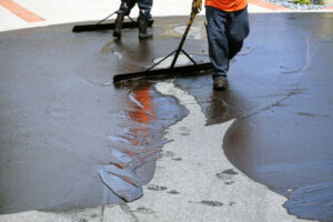 workers laying a sealcoating on asphalt