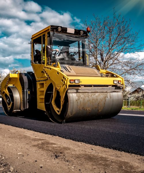Road roller rolling new hot asphalt on the new road. Road construction. Industrial theme