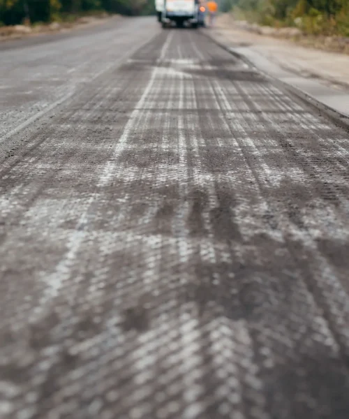 Road milling machine removes asphalt from old road and loads milled asphalt in dump truck.