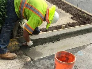 Worker smoothing concrete for curb